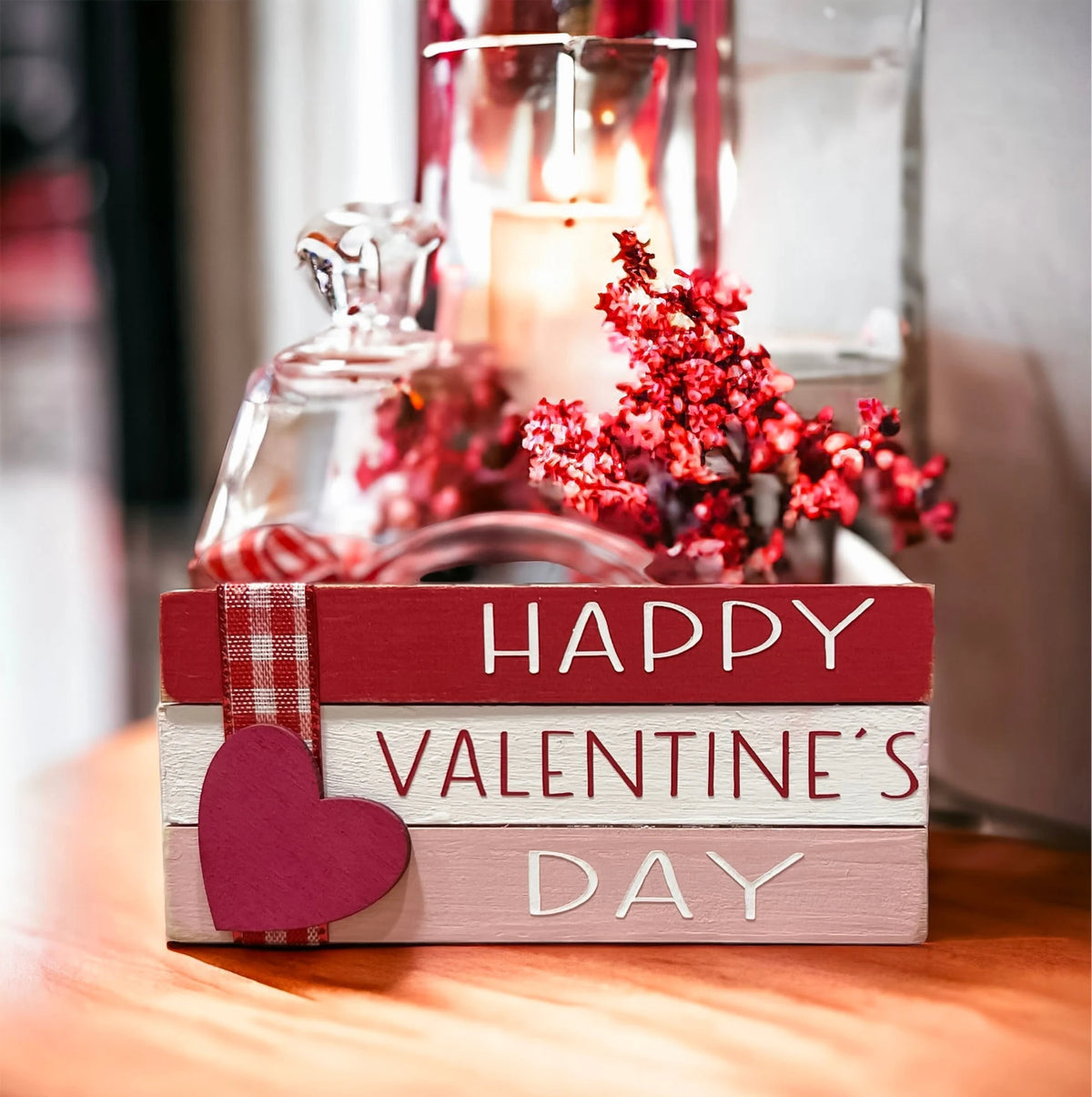 Valentine book stack styled on wood surface with red heart ornaments and pine cones