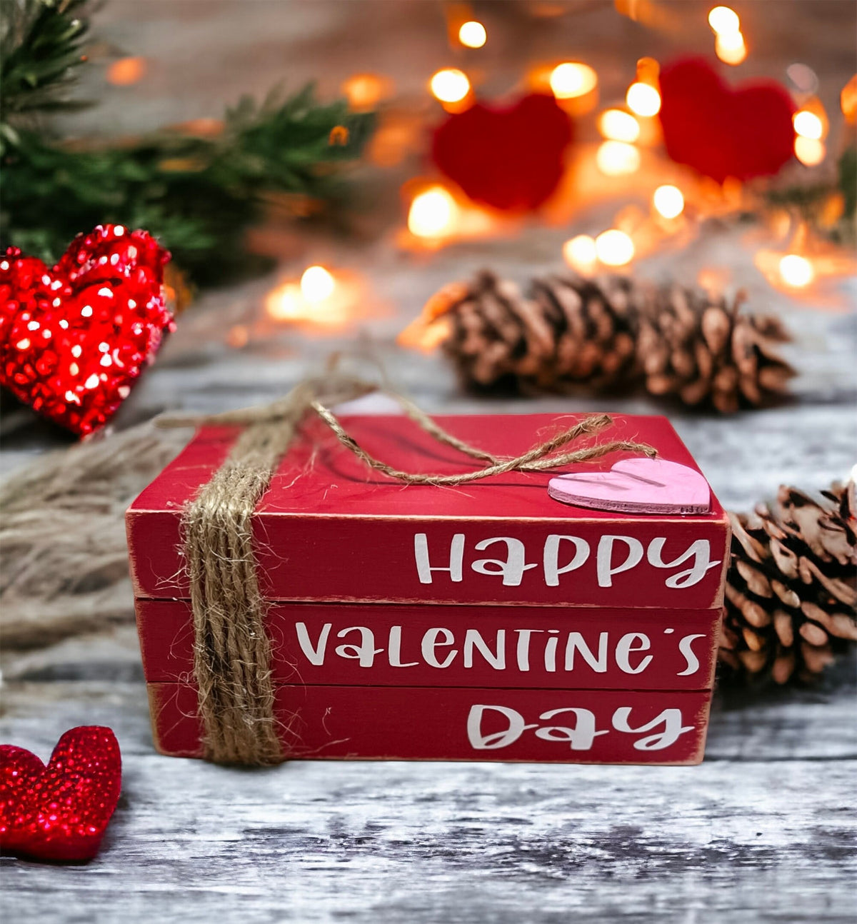 Happy Valentine's Day red wood book stack with jute twine and pink heart product shot on rustic wood surface