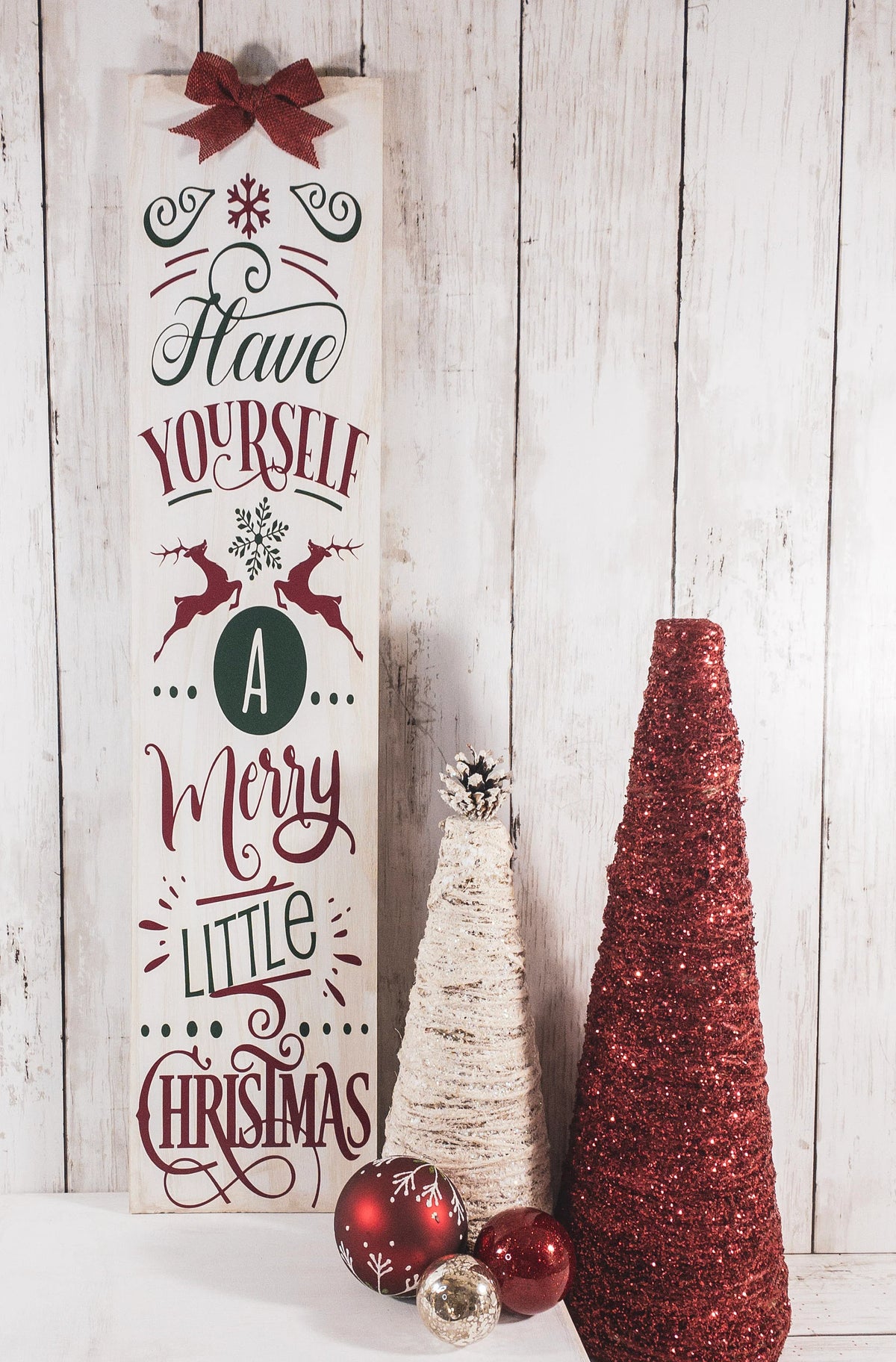Have Yourself a Merry Little Christmas rustic wood porch leaner sign with burlap bow on white wood wall with Christmas garland at base