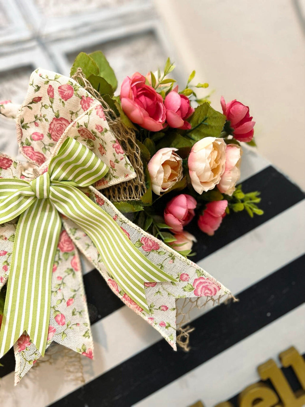 Hello black and white striped round door hanger with pink floral bow on rustic wood front door with lantern and galvanized buckets