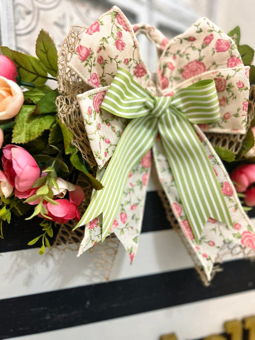 Hello black and white striped round door hanger with pink floral bow on white chair in garden with pink roses