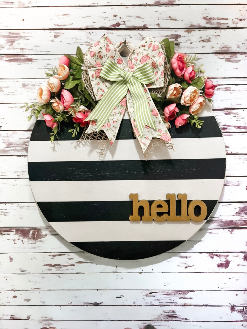 Hello black and white striped round door hanger with pink floral bow product shot on distressed white wood wall