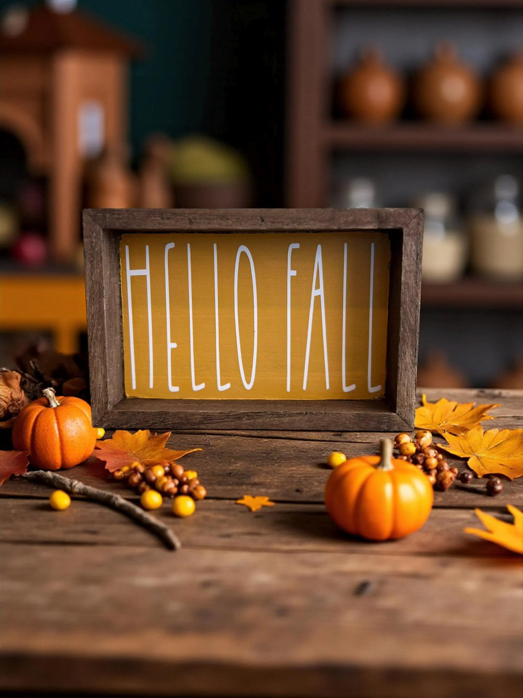 Hello Fall golden yellow framed wood sign on dark wood surface with mini pumpkins and gourds close up