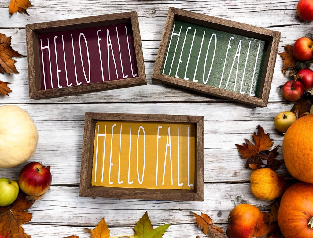 Hello Fall framed wood sign in all three colors cranberry golden yellow and pine green on white wood surface with apples and pumpkins