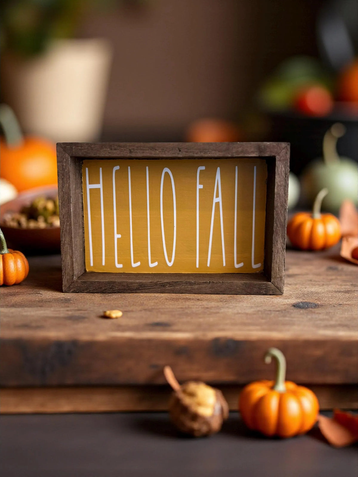 Hello Fall golden yellow framed wood sign on dark wood surface with mini pumpkins and gourds