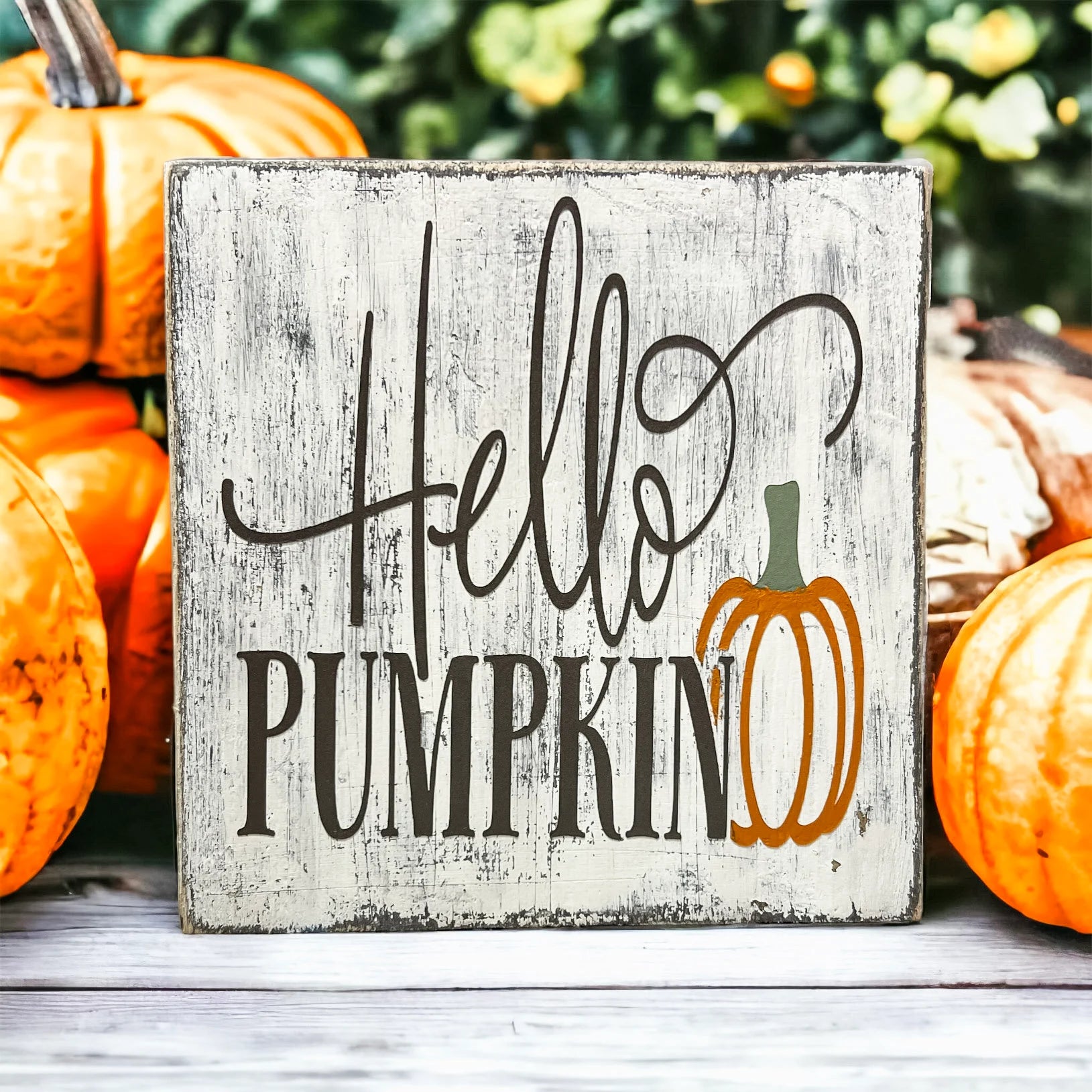 Hello Pumpkin wood block sign with black script and serif lettering and orange pumpkin graphic on distressed white pine on white tiered tray with orange fall flowers and burlap ribbon