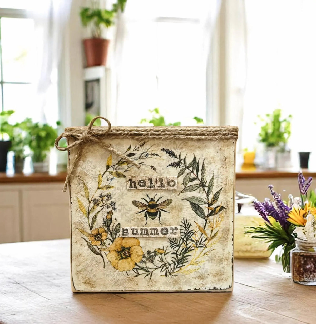 Hello Summer bee sign on white wood surface with sunflowers and pastel background