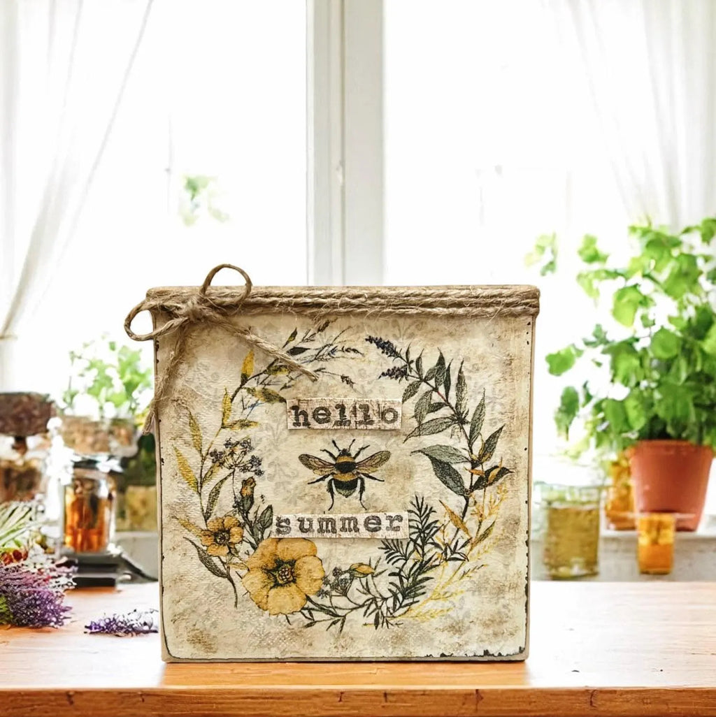 Hello Summer bee sign on wood surface near window with herb plants and honey jars