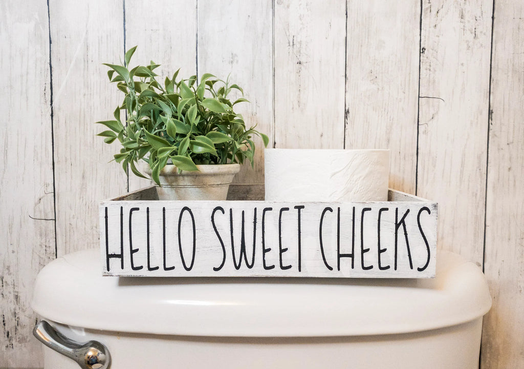 Hello Sweet Cheeks white farmhouse toilet paper box on toilet tank with plant and toilet paper roll