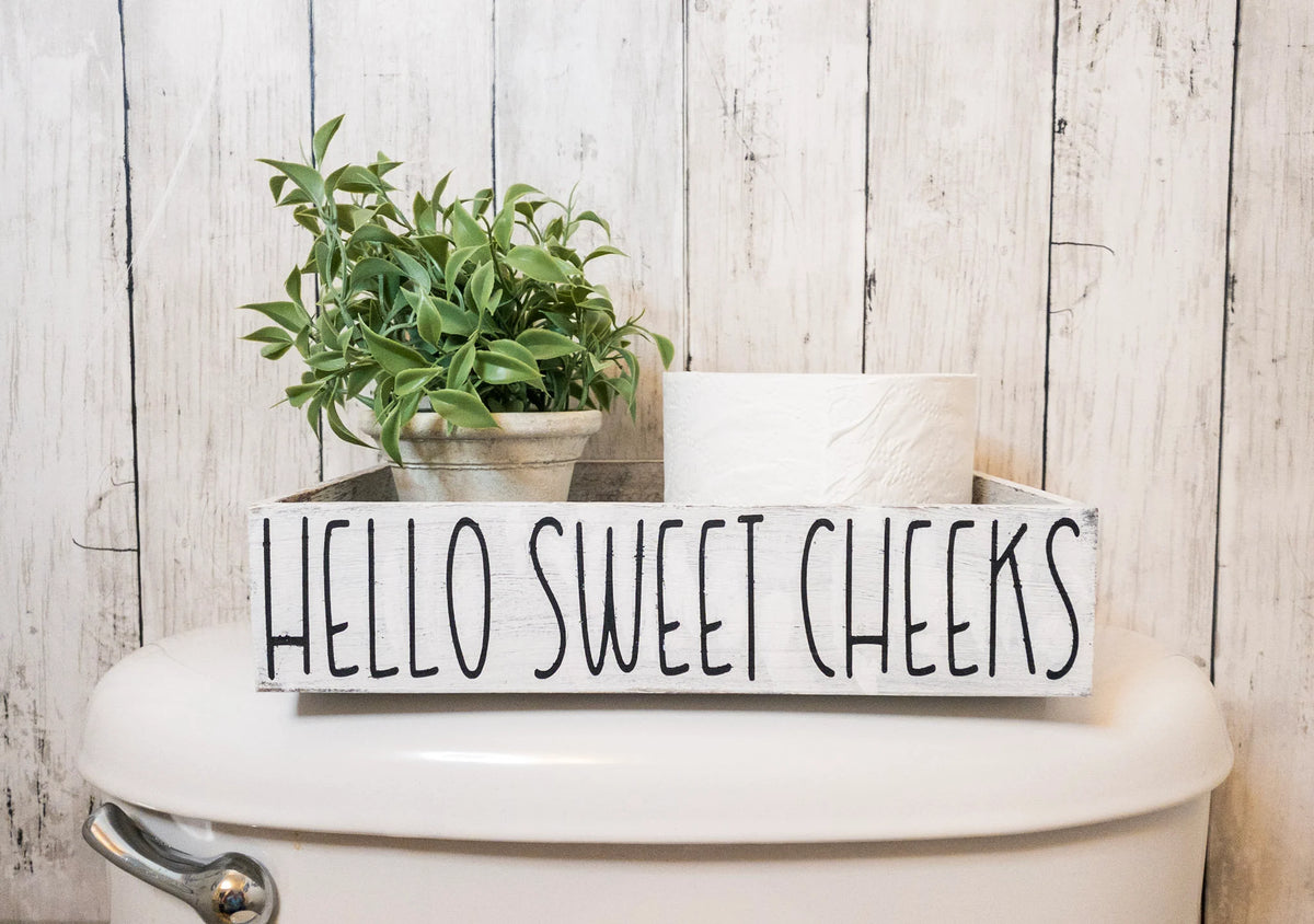 Hello Sweet Cheeks white farmhouse toilet paper box on toilet tank with plant and toilet paper roll