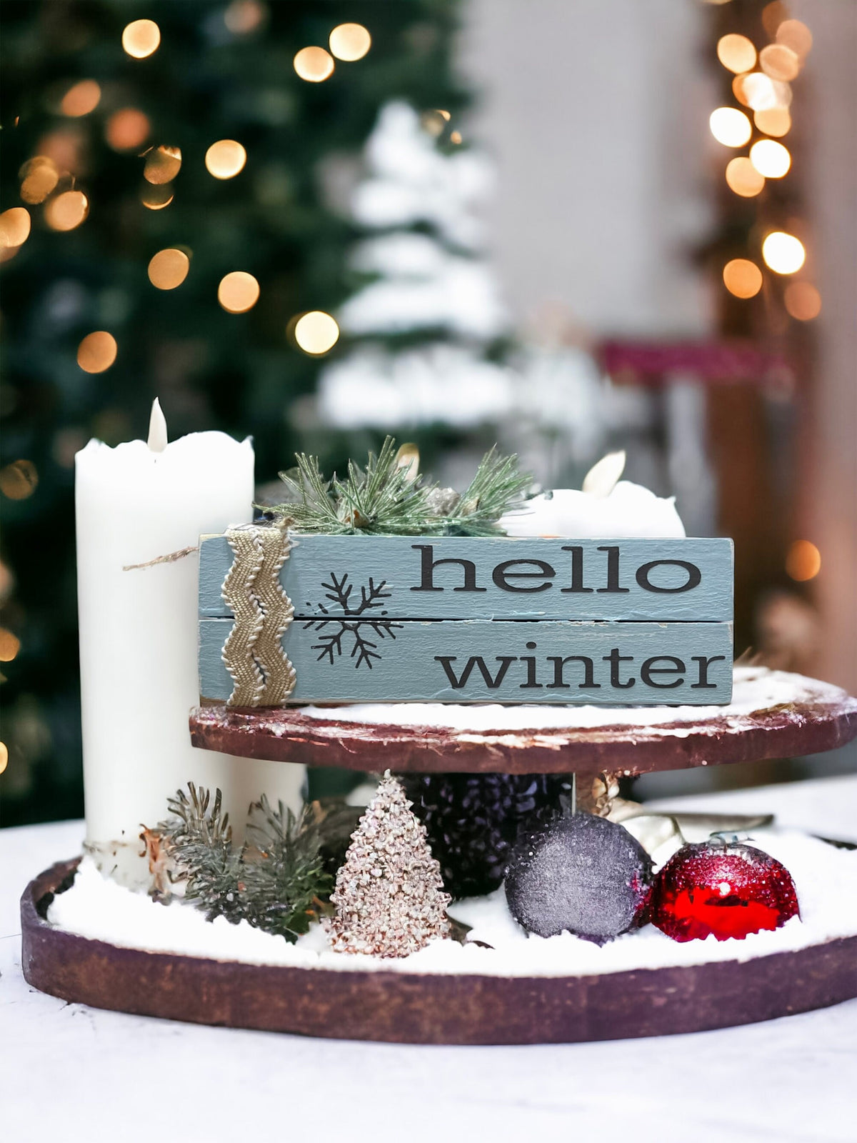 Hello Winter dusty blue wood book stack with snowflake and burlap ribbon on wood shelf with lit bottle brush tree