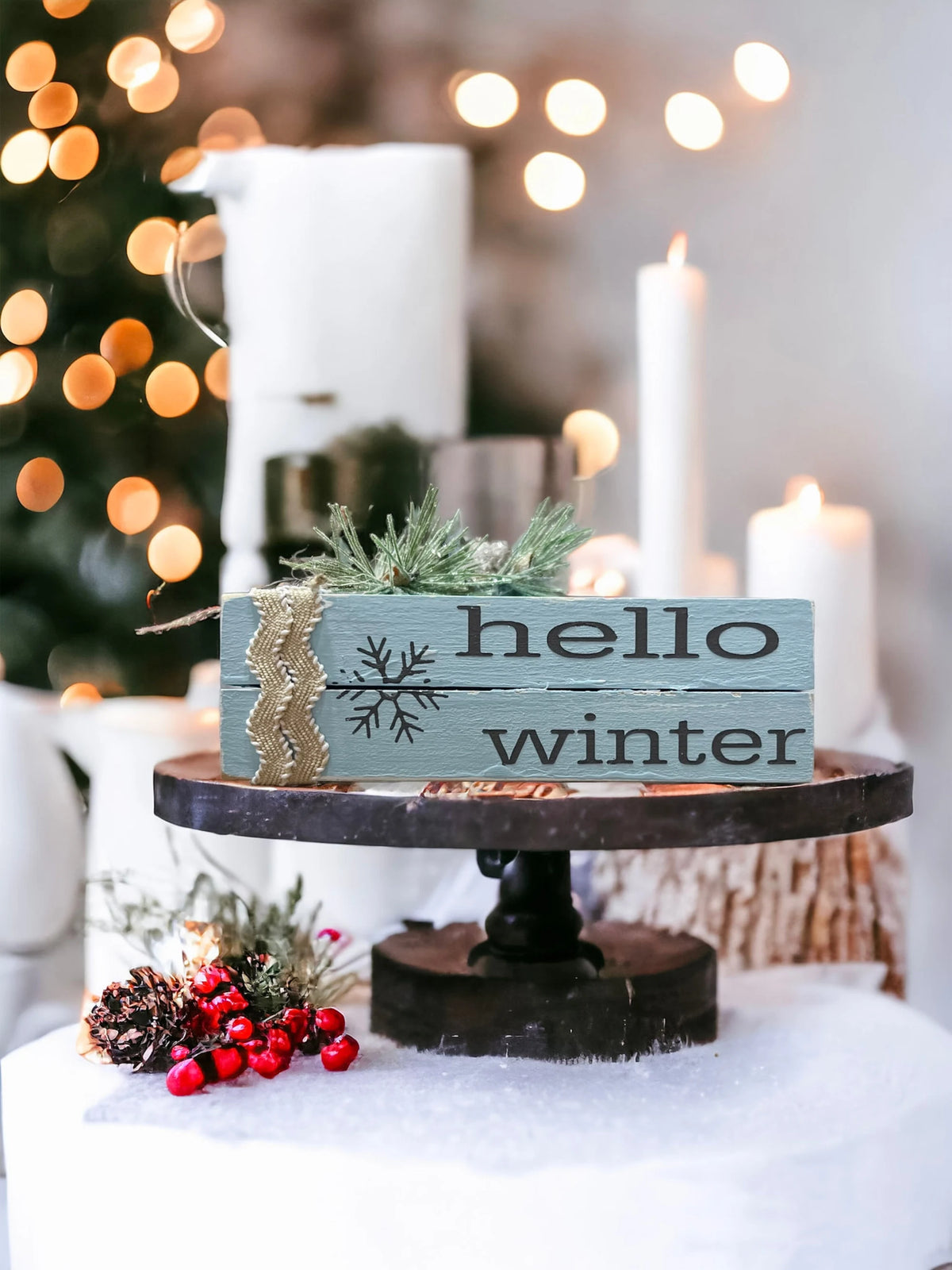 Hello Winter dusty blue wood book stack with snowflake and burlap ribbon product shot on wood surface with Christmas tree bokeh