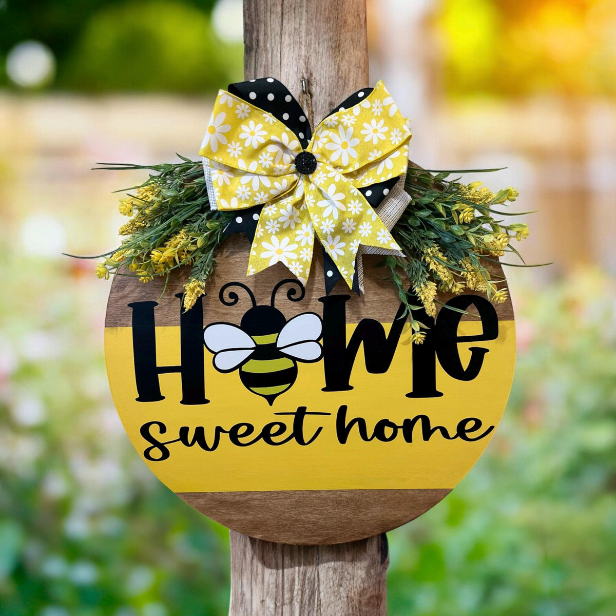 Home Sweet Home bee round pine door hanger yellow and walnut two-tone with daisy polka dot bow and wildflower greenery hung in rustic arched window with brick surround