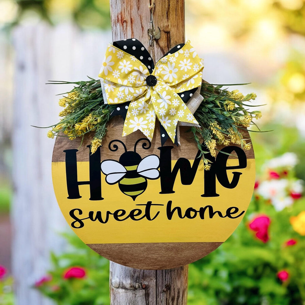 Home Sweet Home bee round pine door hanger yellow and walnut two-tone with daisy polka dot bow and wildflower greenery on rustic wood post in garden bokeh background wide shot