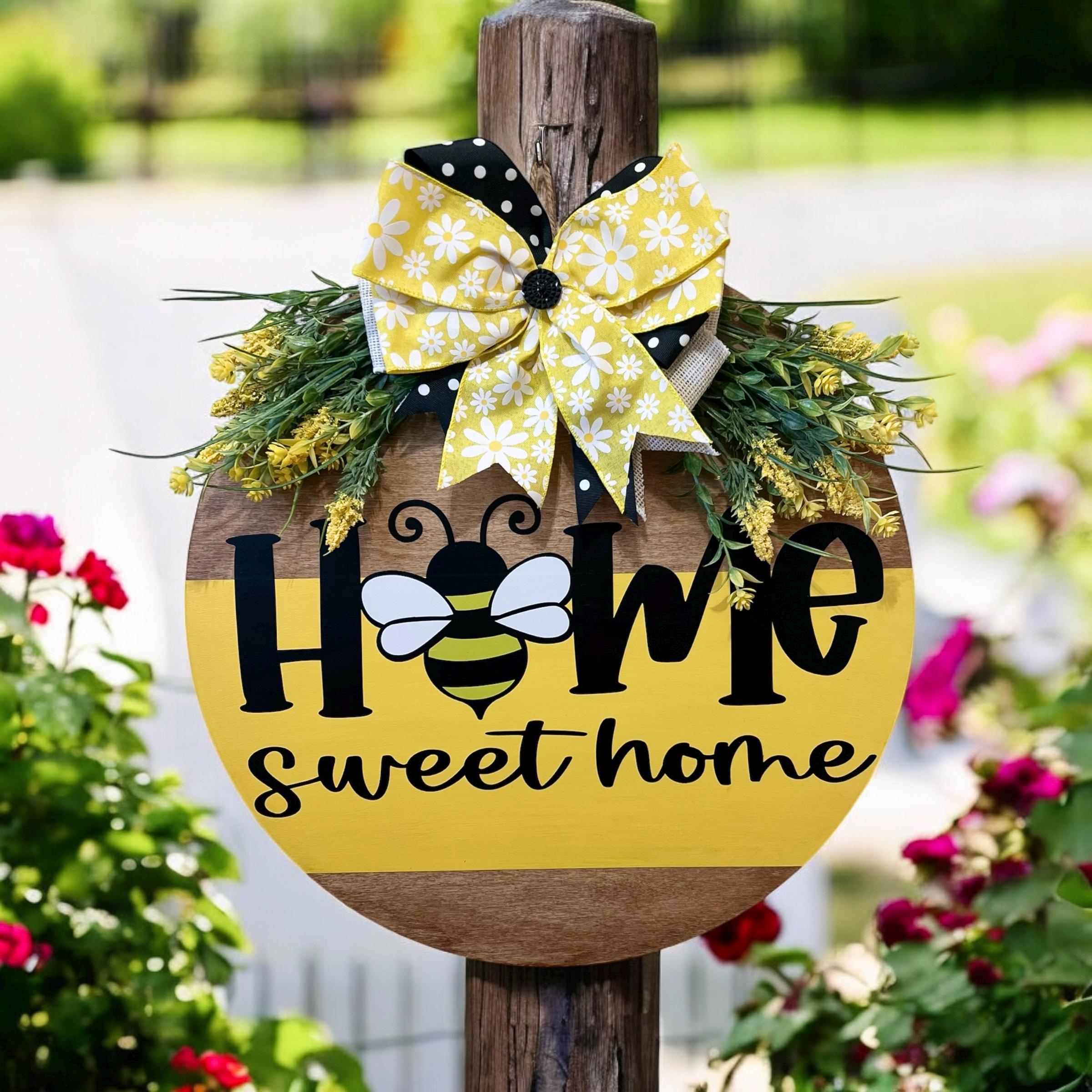 Home Sweet Home bee round pine door hanger yellow and walnut two-tone with daisy polka dot bow and wildflower greenery hung on white door wide lifestyle shot