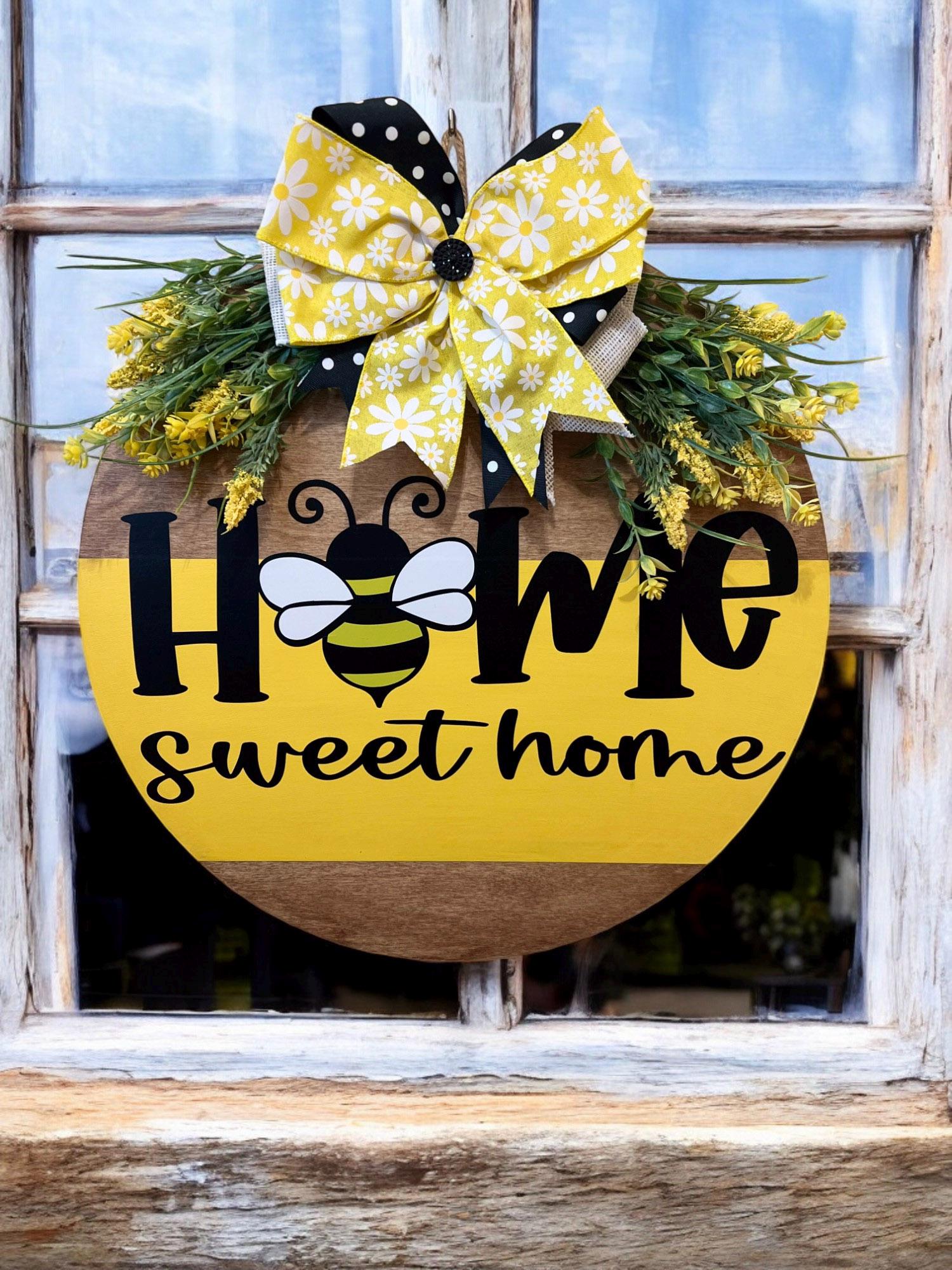 Home Sweet Home bee round pine door hanger yellow and walnut two-tone with daisy polka dot bow and wildflower greenery hung on white door close up front view