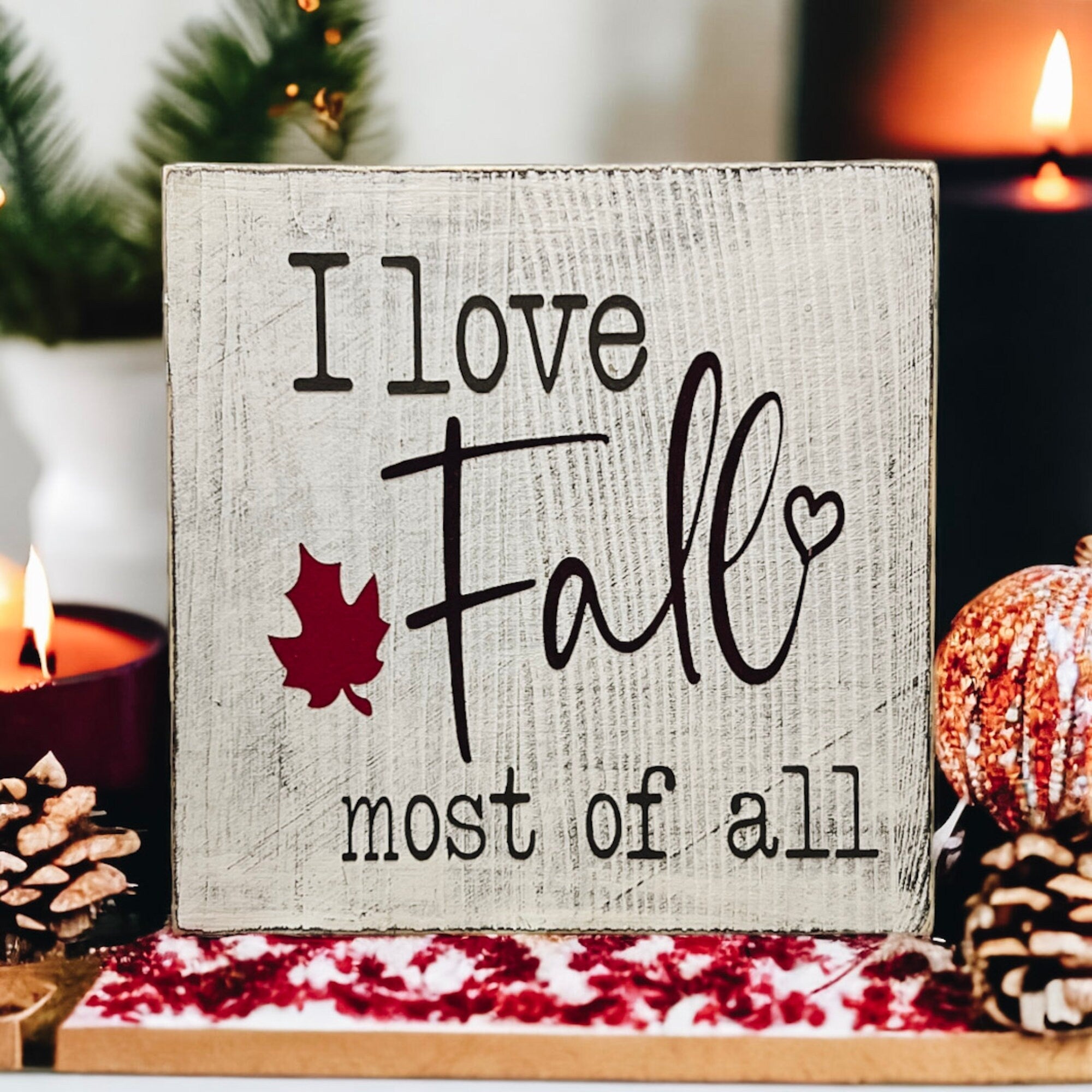 I Love Fall Most of All distressed off-white wood block sign with black lettering and burgundy maple leaf on round wood tray with glass candle jar white pumpkins and cinnamon sticks