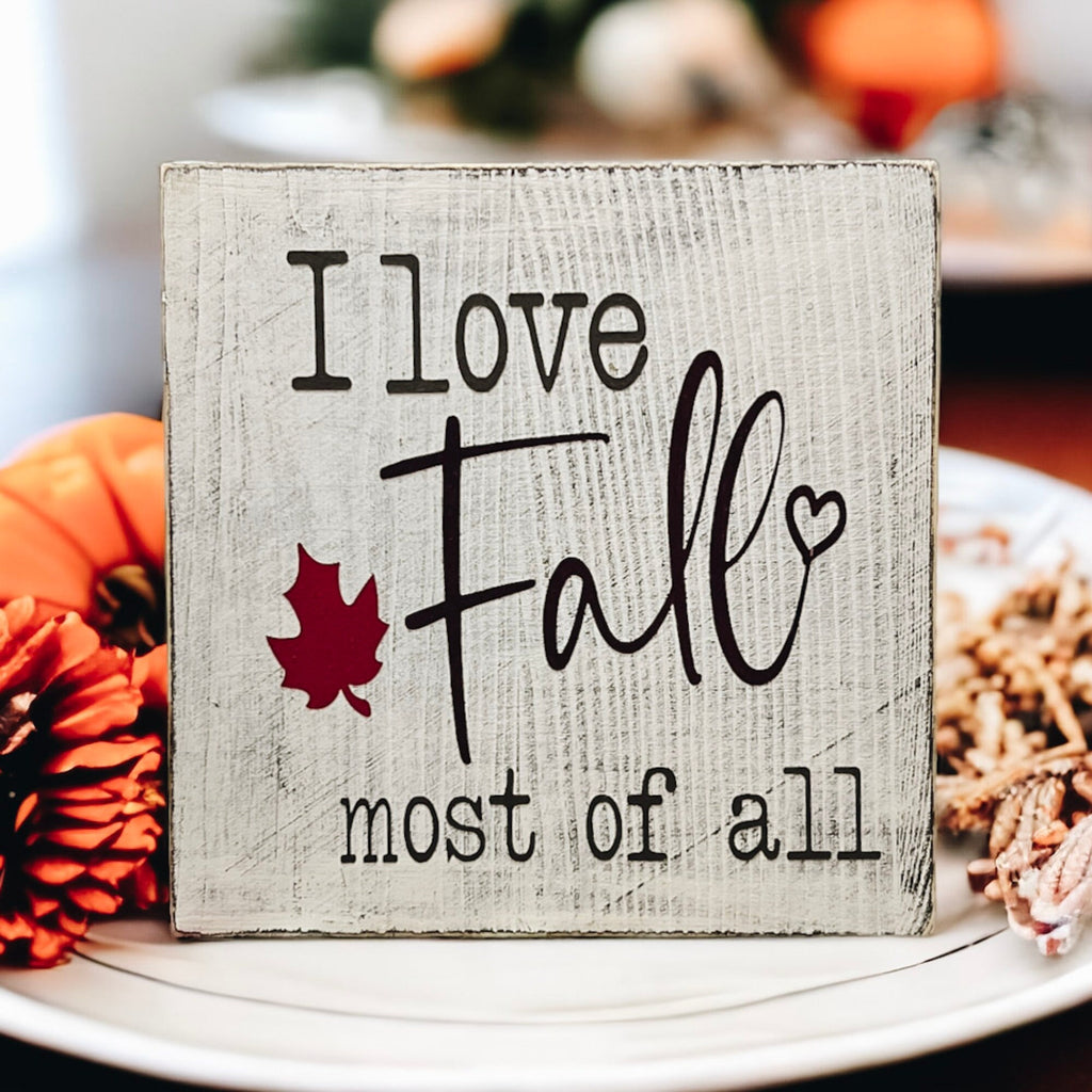 I Love Fall Most of All distressed off-white wood block sign with black lettering and burgundy maple leaf product hero shot on white background