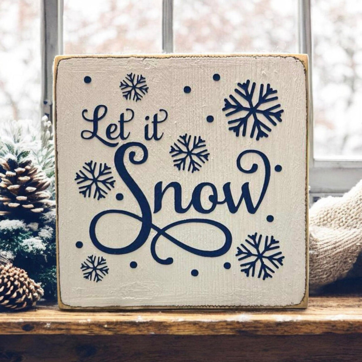 Let It Snow sign on farmhouse table with holiday garland and bead strand