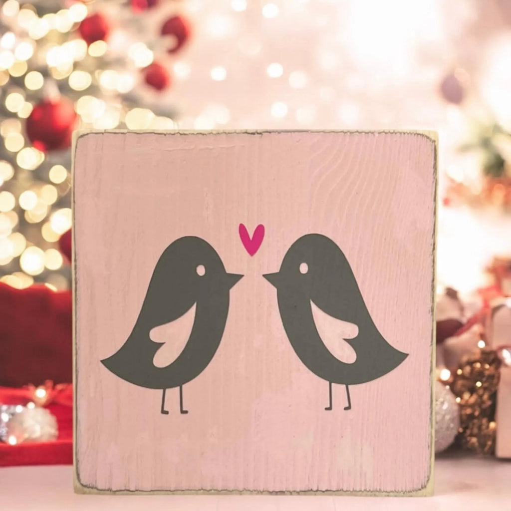 Lovebirds Valentine wood block sign on white wood surface with pink carnations and roses