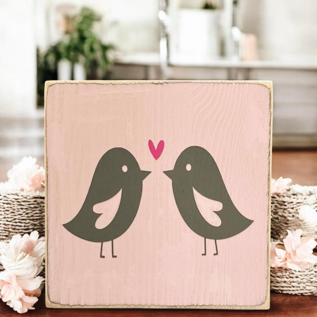 Lovebirds Valentine wood block sign on wood surface with pink and red roses close up