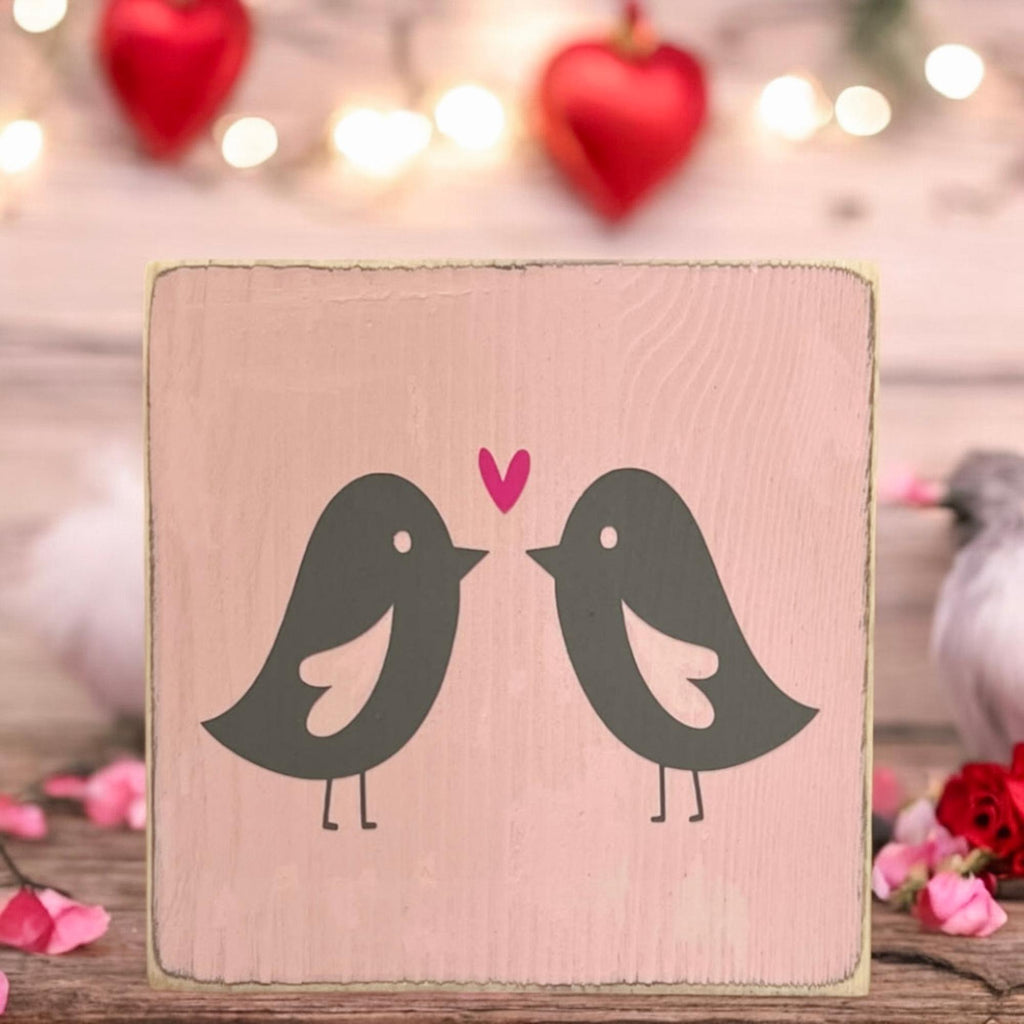 Lovebirds Valentine wood block sign on wood shelf with red heart lights and red roses in background