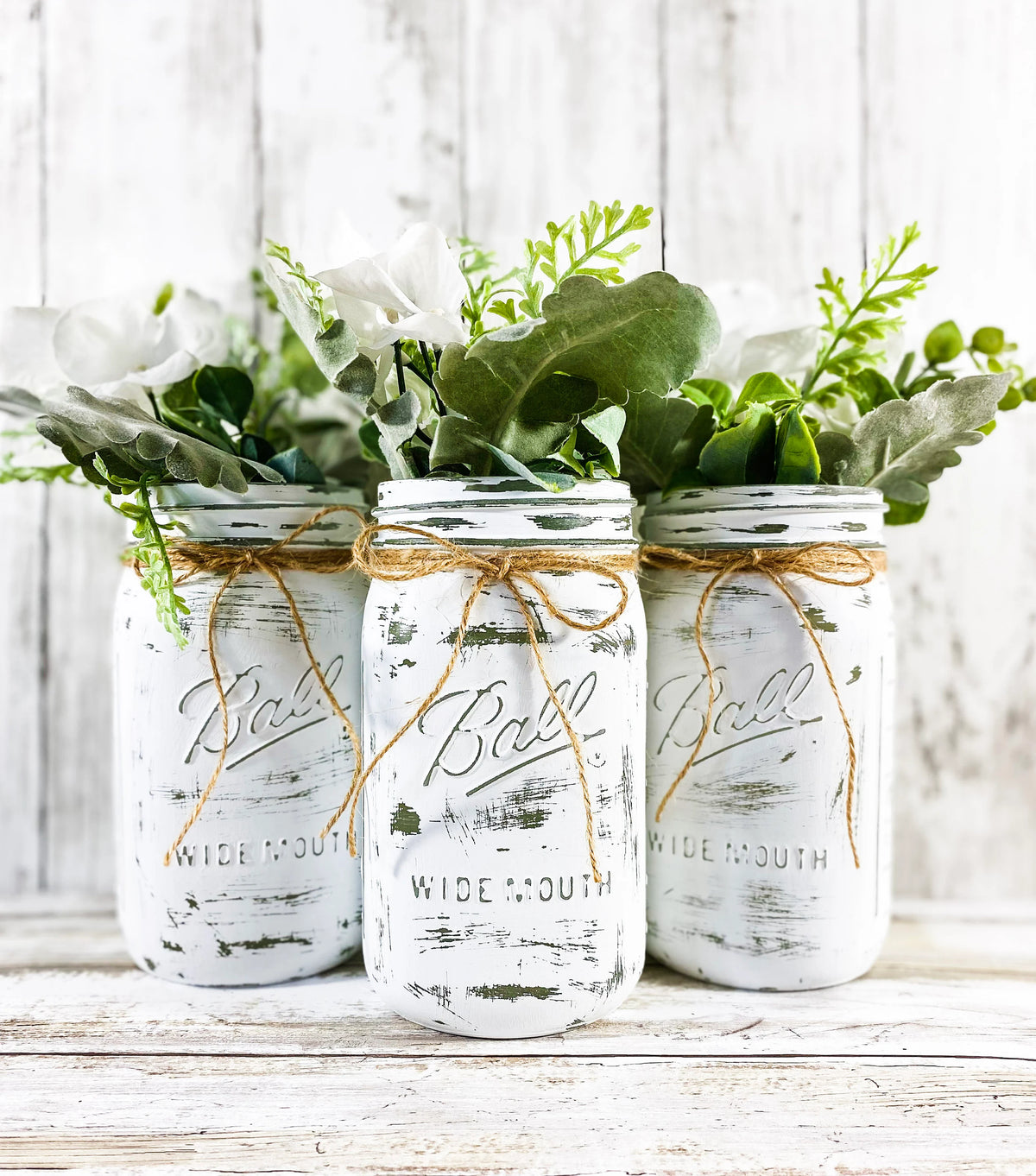 Single white distressed Ball mason jar with fall pumpkins and autumn leaves