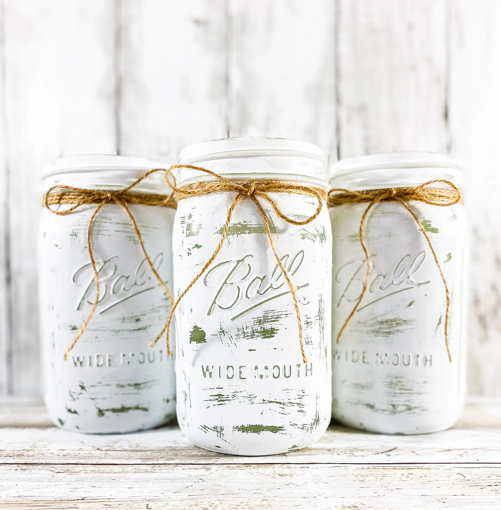 Single white painted Ball mason jar with jute bow on wood table with staircase background