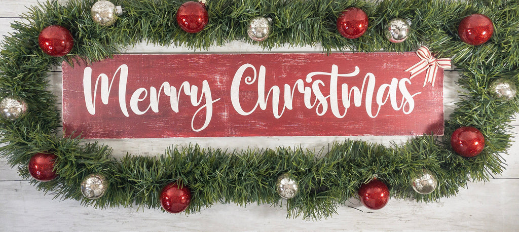 Merry Christmas farmhouse wood sign distressed cranberry red with white script lettering and red white striped bow on white shiplap wall wide shot