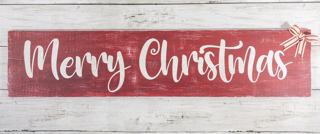 Merry Christmas farmhouse wood sign distressed cranberry red with white script lettering and red white striped bow surrounded by pine garland with red and silver ornaments on white shiplap