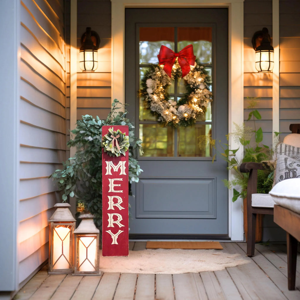 MERRY porch leaner sign with holly wreath on warm lit porch with Christmas tree and ornaments in background