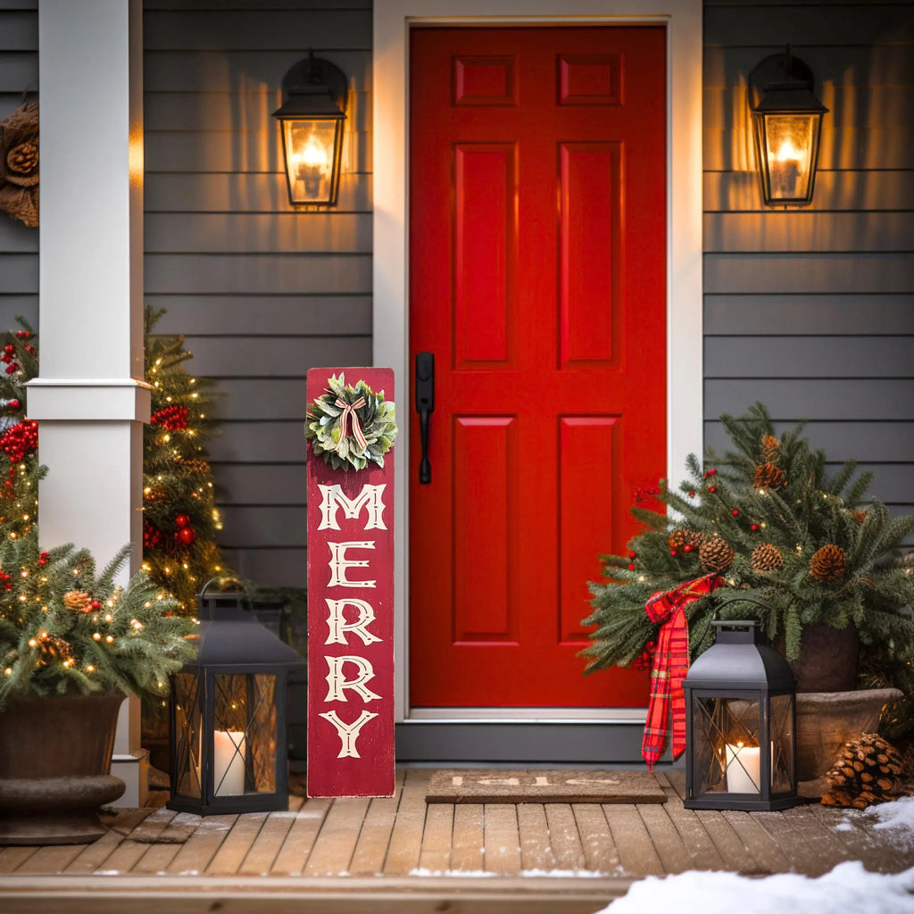 MERRY porch leaner sign with holly wreath leaning against red front door with Christmas greenery and lanterns wide view