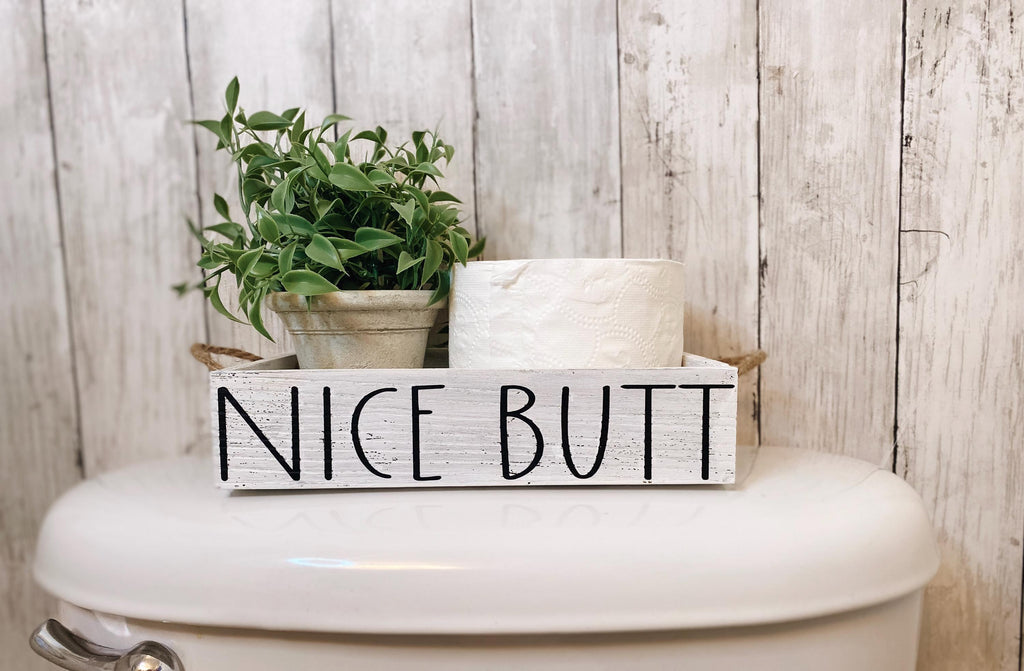 Nice Butt white farmhouse toilet paper box on toilet tank with plant and toilet paper roll