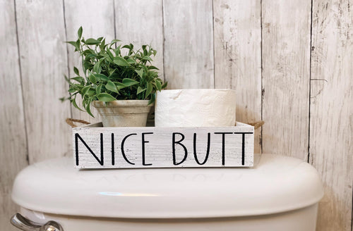 Nice Butt white farmhouse toilet paper box on toilet tank with plant and toilet paper roll