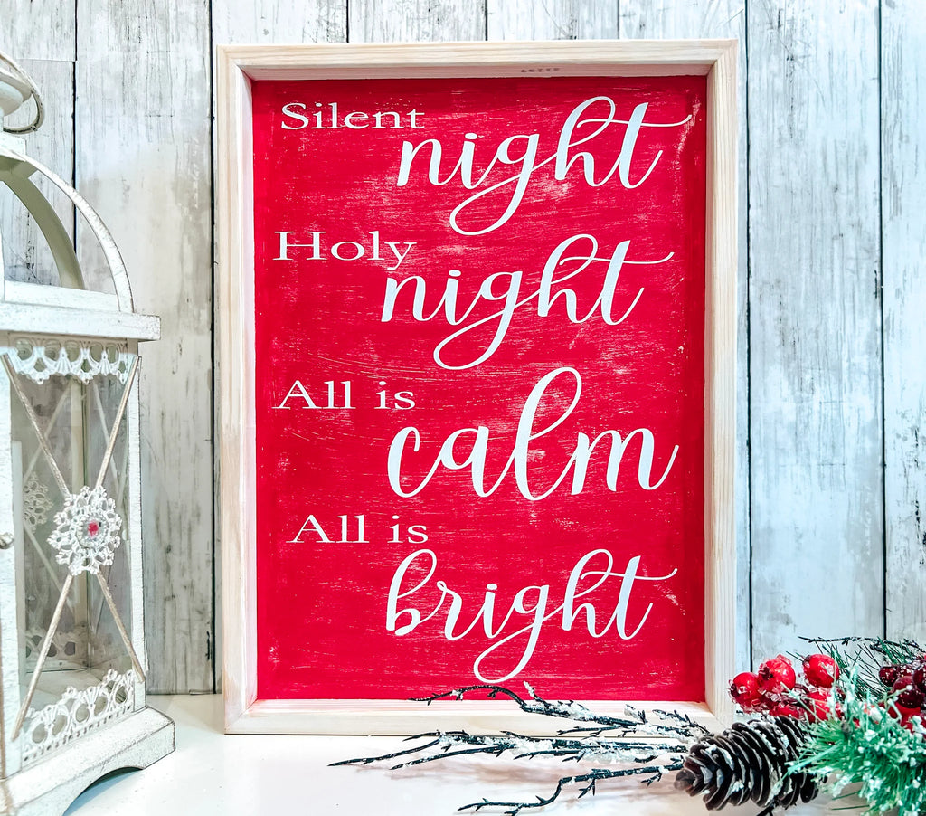 Red Silent Night Holy Night All is Calm All is Bright framed wood sign with whitewashed birch frame leaning against white shiplap wall with white lantern and red berry pine cone spray wide shot