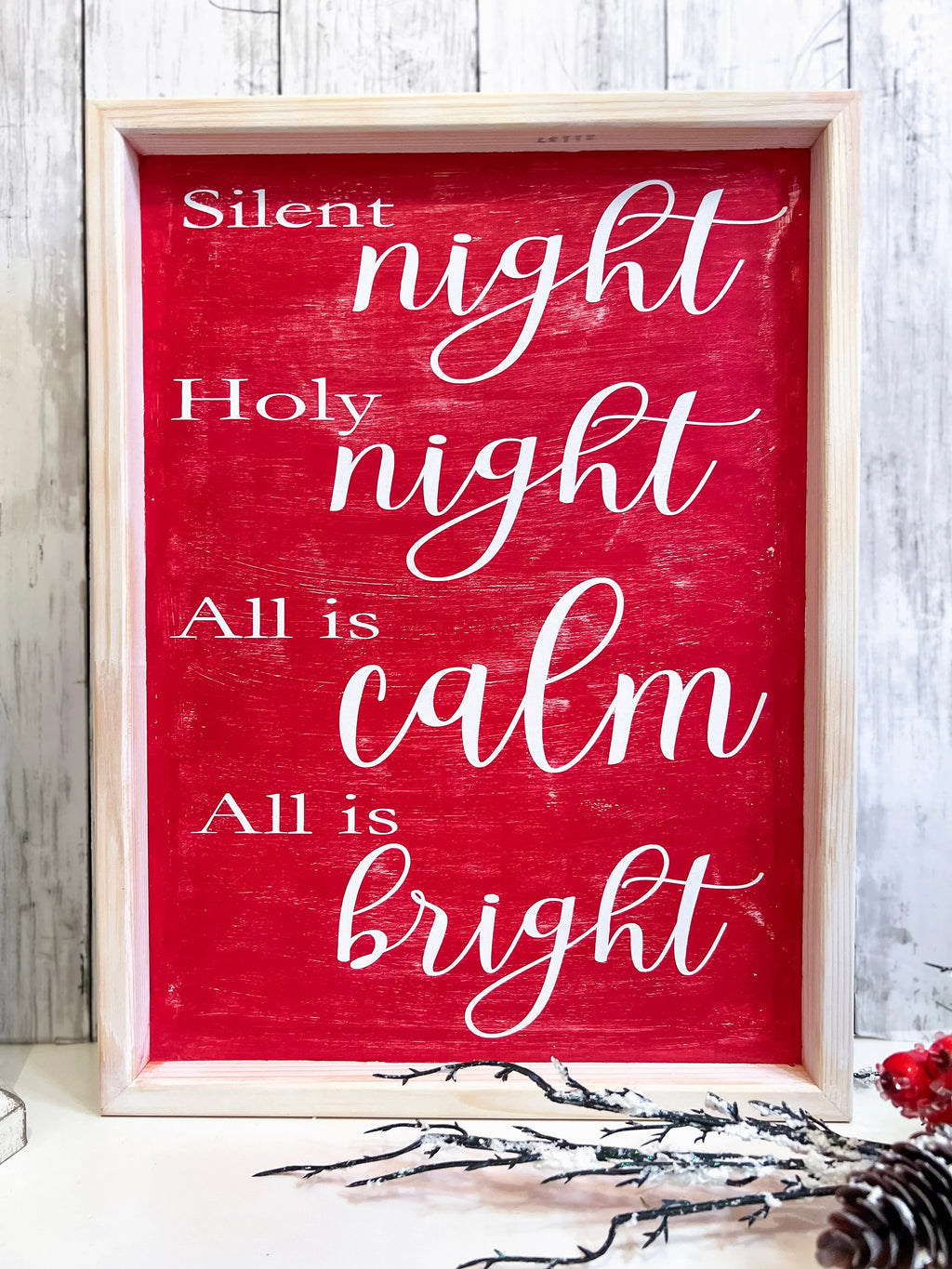 Red Silent Night Holy Night All is Calm All is Bright framed wood sign with whitewashed birch frame leaning against white shiplap wall with white lantern and red berry pine cone spray