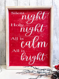 Red Silent Night Holy Night All is Calm All is Bright framed wood sign with whitewashed birch frame leaning against white shiplap wall with white lantern and red berry pine cone spray