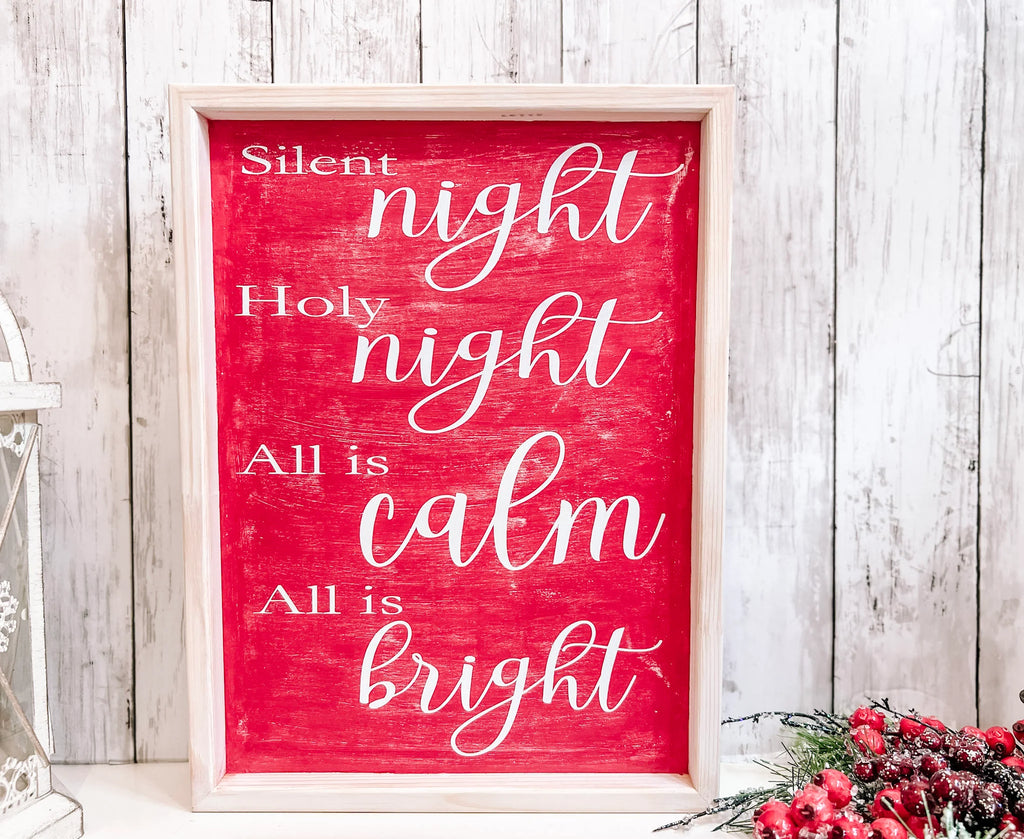 Red Silent Night Holy Night All is Calm All is Bright framed wood sign with whitewashed birch frame leaning against white shiplap wall with white lantern and red berry pine cone spray hero shot
