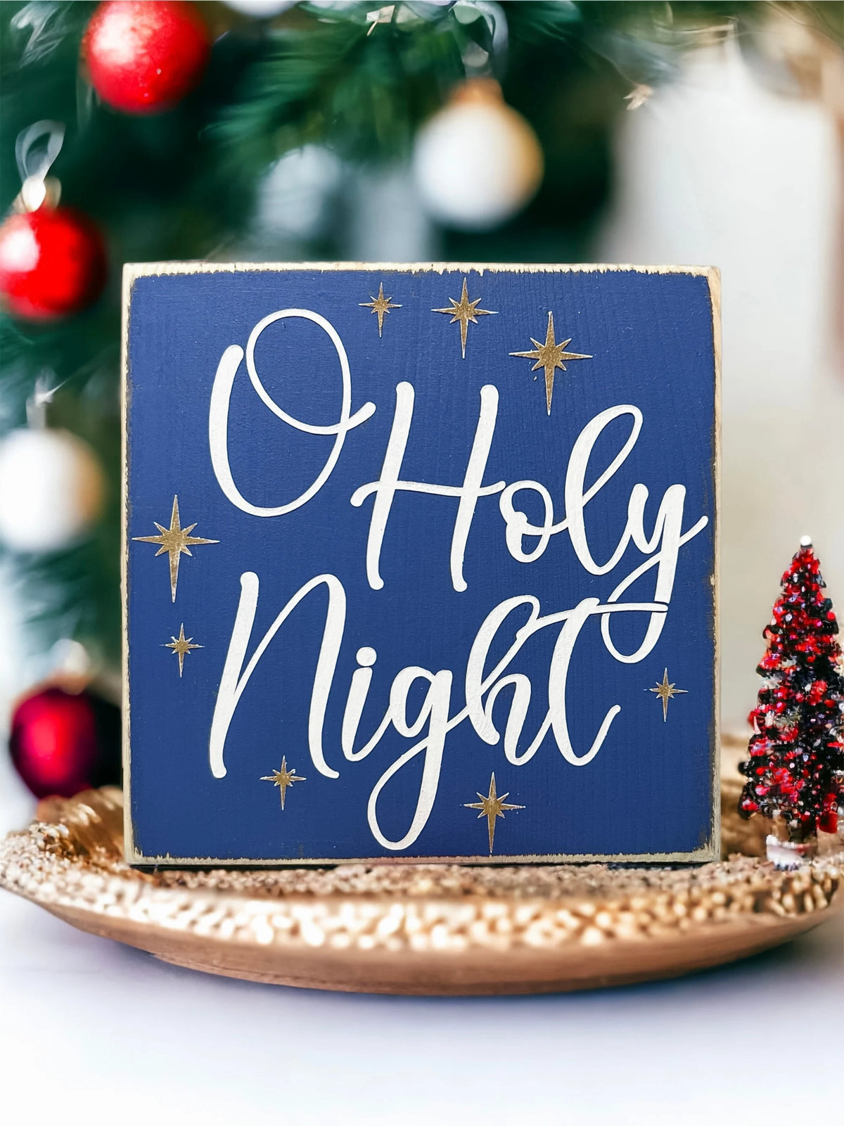 Oh Holy Night navy blue wood block sign with white script and gold stars on snowy tiered tray with flocked mini trees and ornaments