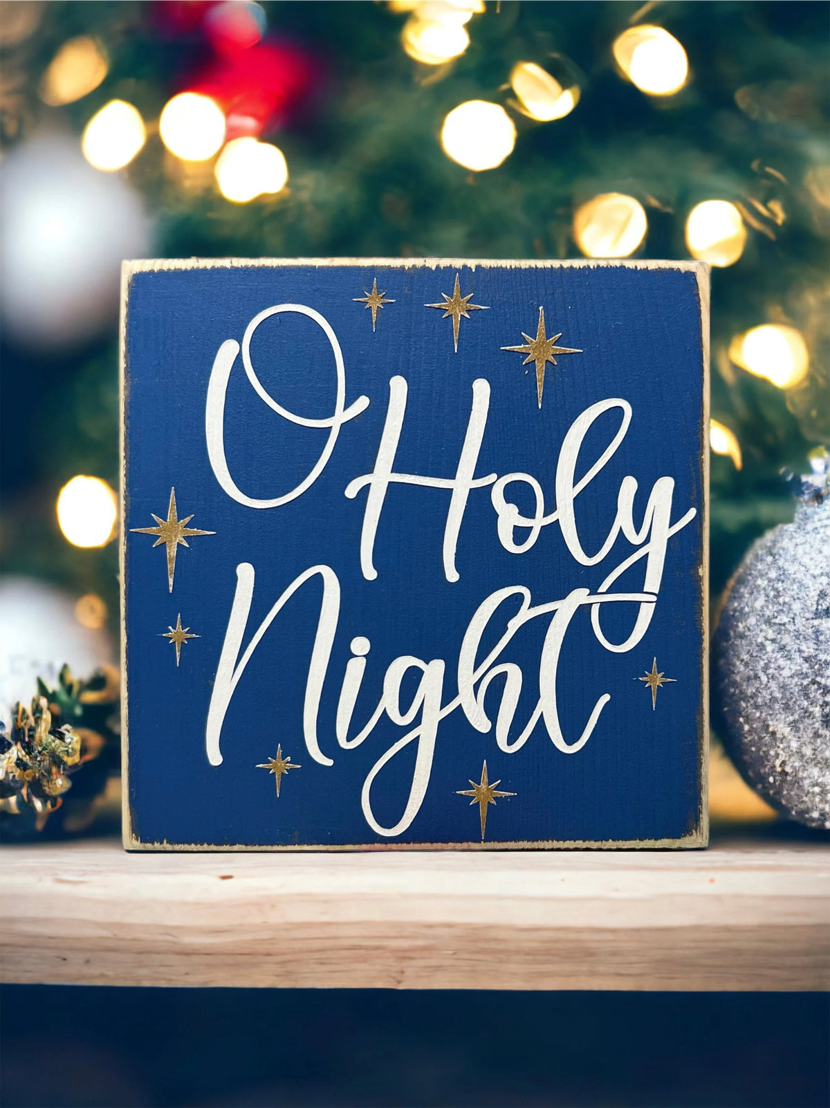 Oh Holy Night navy blue wood block sign with white script and gold stars on gold tiered tray with mini Christmas tree and ornaments