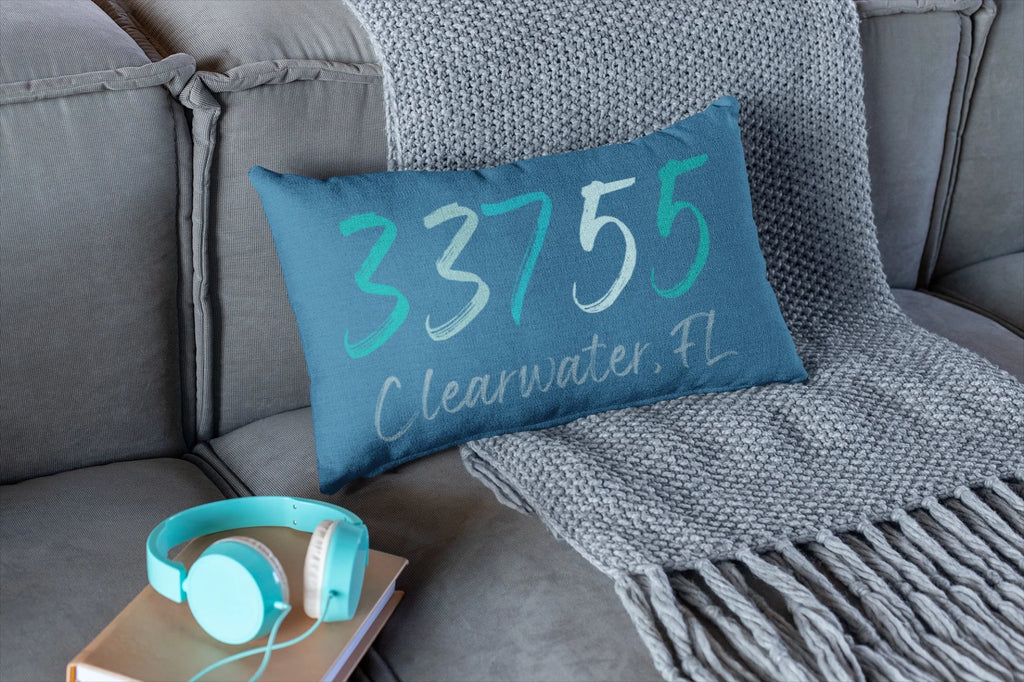 Personalized 33755 Clearwater FL navy lumbar pillow on leather sofa with rust throw pillow and woven blanket lifestyle shot