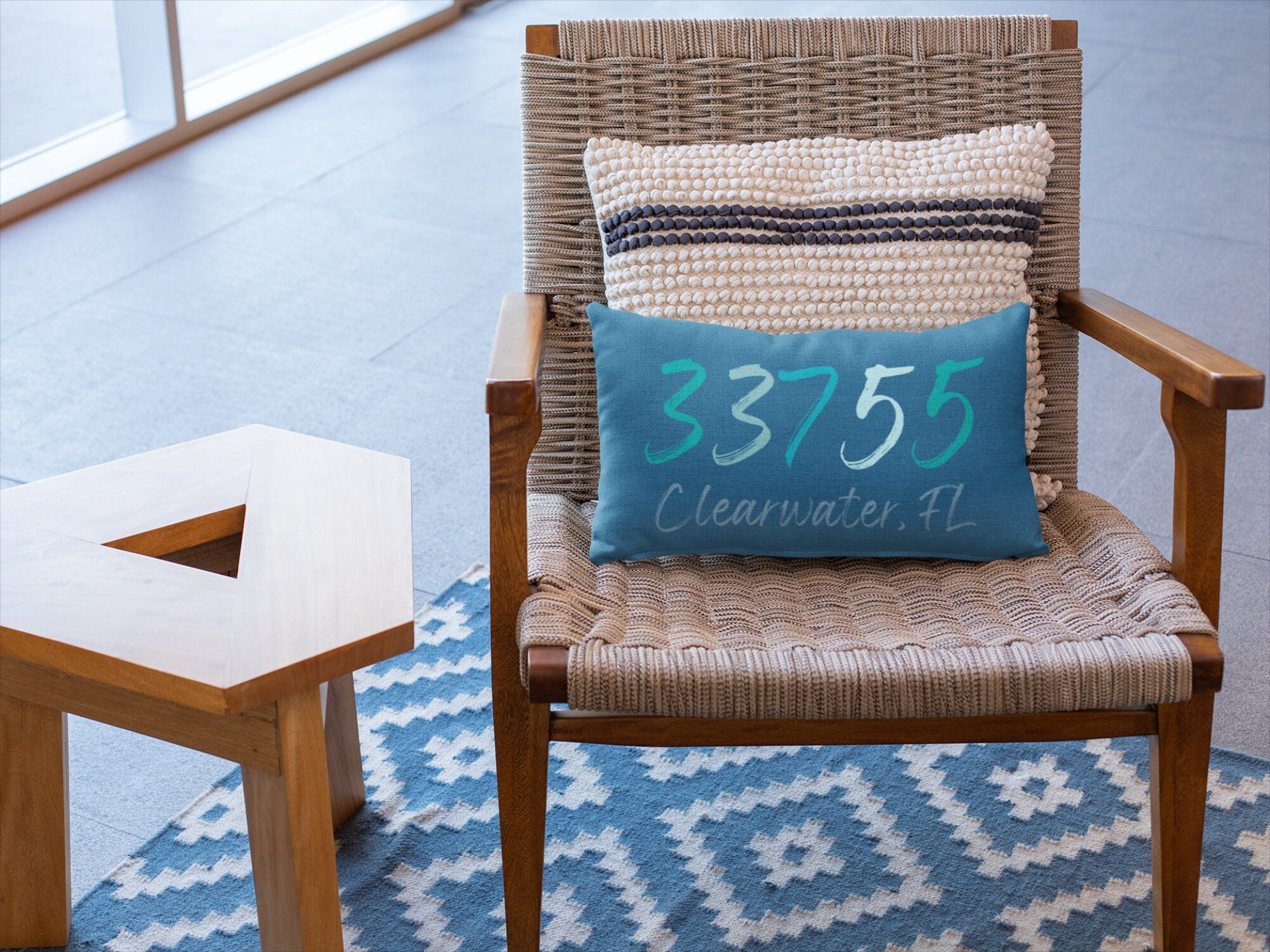 Personalized 33755 Clearwater FL navy lumbar pillow on woven rattan chair with blue diamond rug close up