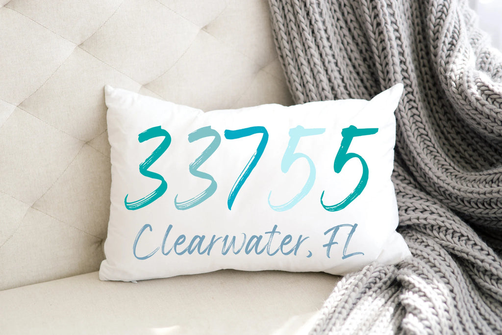 Personalized zip code lumbar pillow reading 33755 Clearwater FL in coastal teal blues product flat lay on white background