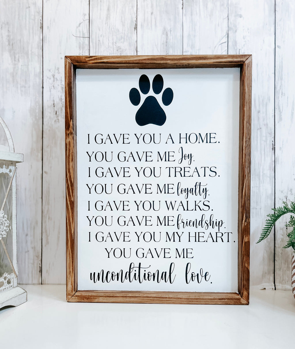 Personalized pet memorial sign with black paw print and unconditional love lettering on white background with dark walnut frame close up