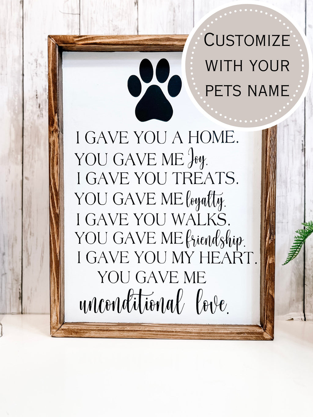 Personalized pet memorial sign with dark navy paw print and unconditional love lettering styled with white lantern and green plant