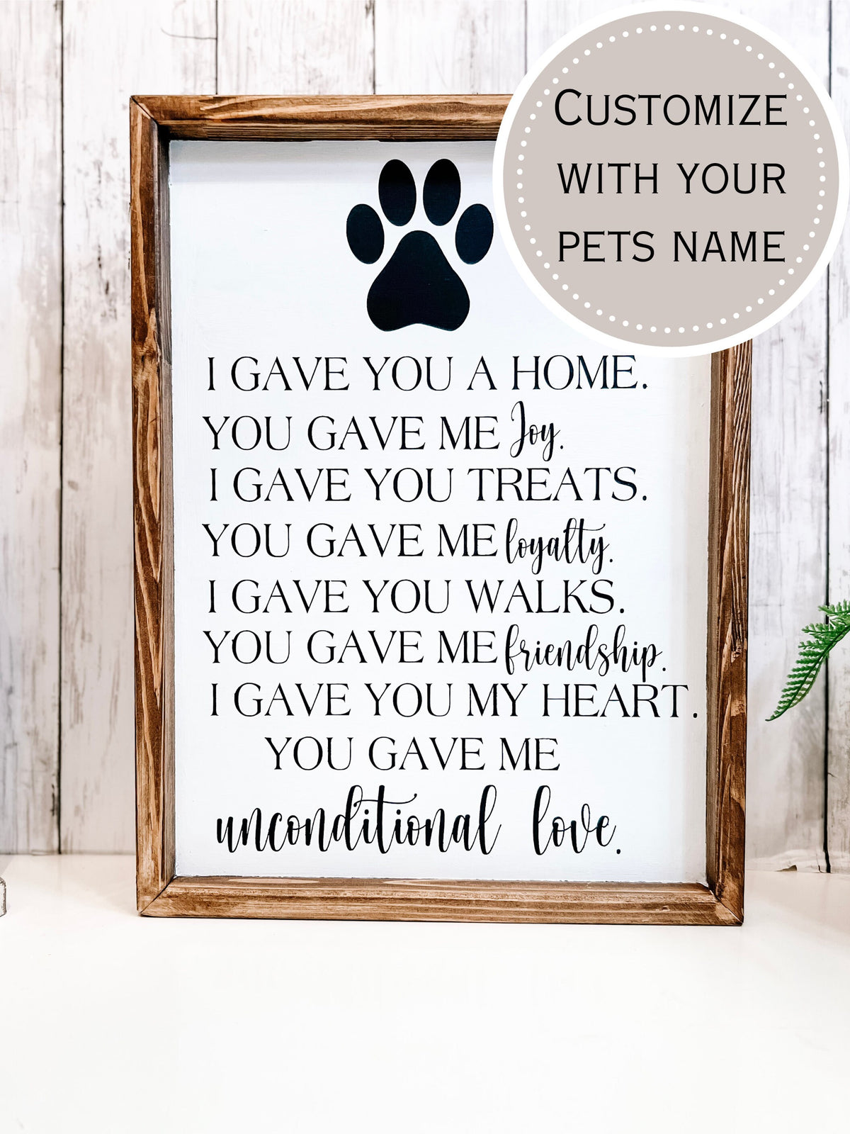 Personalized pet memorial sign with dark navy paw print and unconditional love lettering styled with white lantern and green plant
