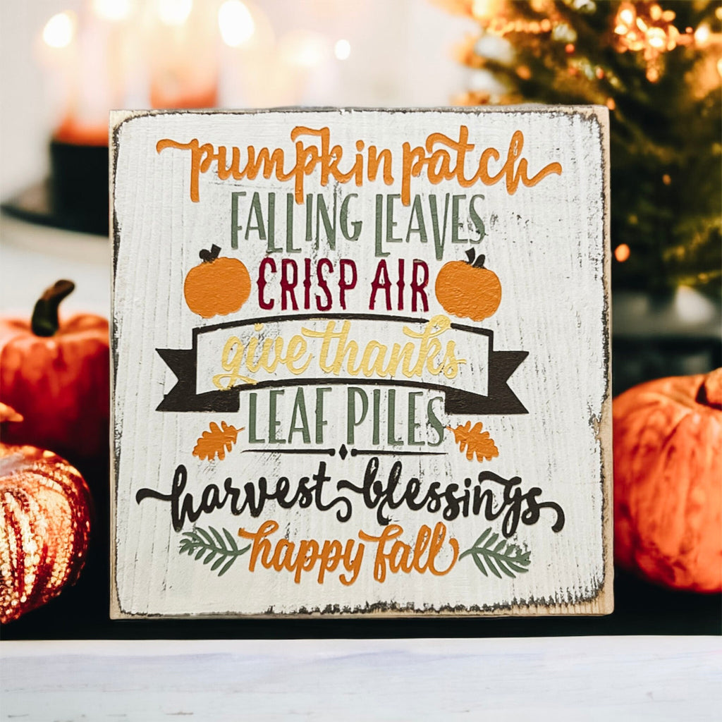Fall sign on rustic wood surface with autumn leaves and cozy textile