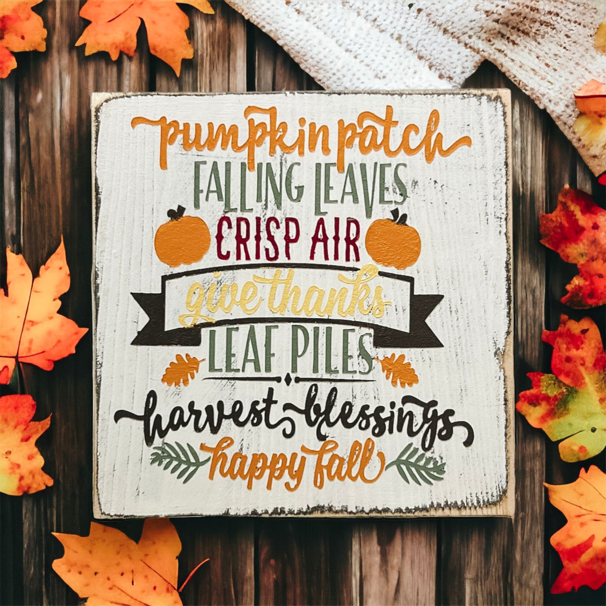Fall sign on wood deck surrounded by large orange pumpkins