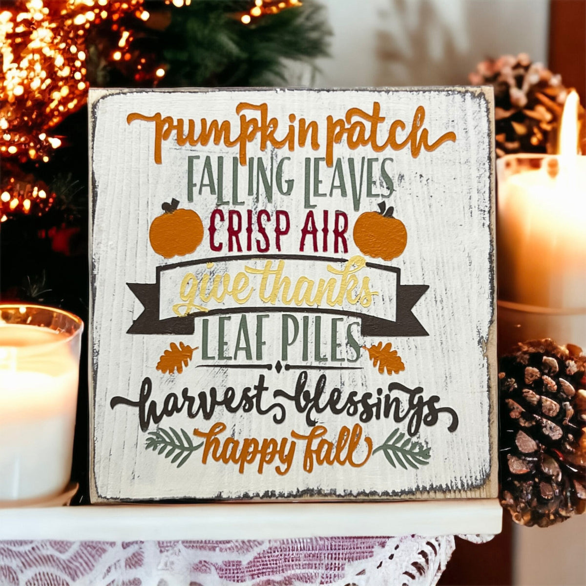 Fall sign on dark surface surrounded by orange and red pumpkins with holiday lights