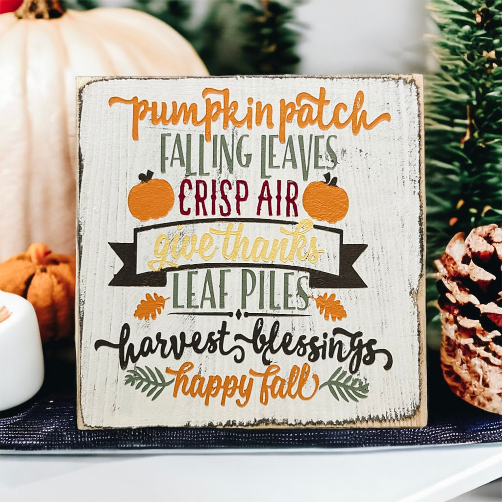 Fall sign on white cake stand with glitter pumpkins and holiday lights